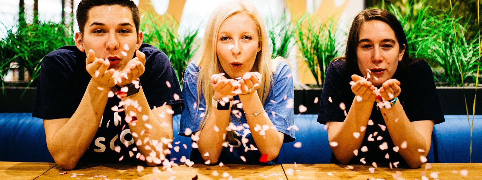 Male and two females blowing confetti from their palms in celebration from Cisco office in Raleigh, North Carolina